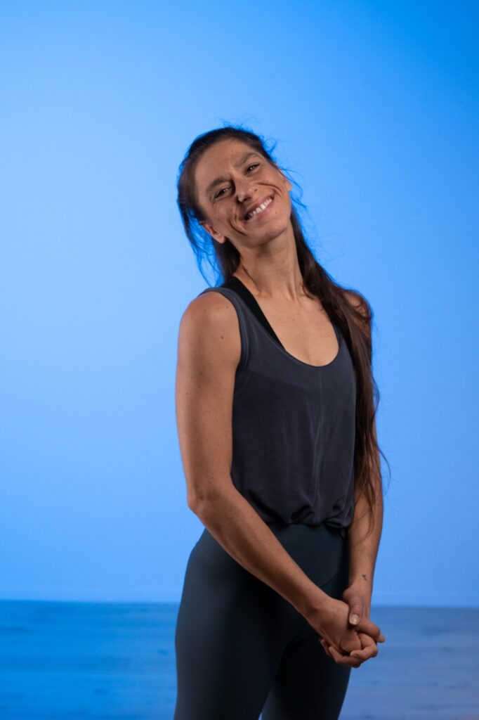 Claudia Di Filippo sorride a occhi chiusi, fondale azzurro